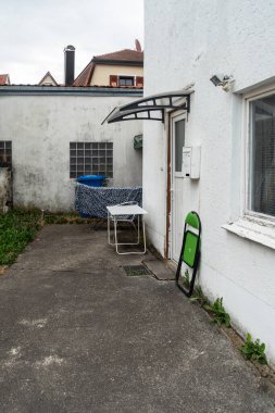 Güney Almanya 'daki ev girişinde çöp tenekesi ve mobilyaları olan eski bir teras.