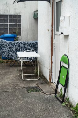 Güney Almanya 'daki ev girişinde çöp tenekesi ve mobilyaları olan eski bir teras.