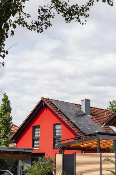 new building with solar panel on rooftop and red house facade with cloudy sky weather in south germany new building area