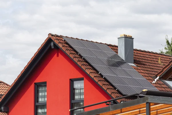 Neubau Mit Solaranlage Auf Dach Und Roter Hausfassade Bei Bewölktem Stockfoto