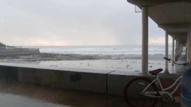 Yağmurlu havada Ocean Beach rıhtımı, sisli havada deniz dalgaları, Kaliforniya kıyıları, ABD. San Diego 'da, deniz kıyısındaki rıhtımda. Şiddetli sağanak altında puslu ve dramatik bir sahil. Demiryolu damlaları.