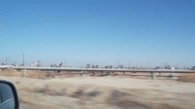Kaliforniya, ABD 'de petrol sahasında pompalı valeleri olan kuyular. Petrol sahasında çalışan ham fosil çıkarma ekipmanları. Endüstriyel arazi, çöl vadisindeki raylar. Petrol kuyularında pompalayan birçok pompa platformu.