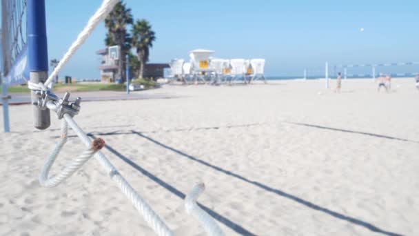 ビーチでバレーボールをしたり カリフォルニア海岸のライフガード小屋で遊んでいる人たち ヤシの木や屋外スポーツフィールド 遊び場や砂浜の海岸の裁判所 ミッションビーチでネットとボールとレクリエーションゲーム — ストック動画