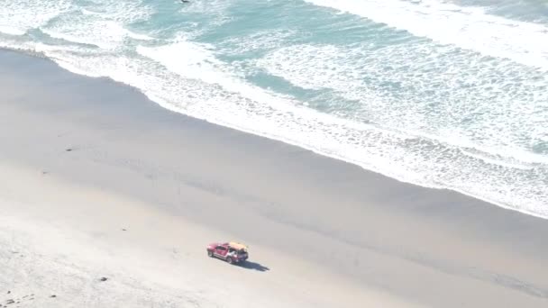 救生员红色皮卡 救生员汽车在沙滩上 加利福尼亚海滨美国 救援人员在海岸拾起汽车 以保证航行安全 救援人员的车辆和海浪从上方涌来 托里松林悬崖 — 图库视频影像