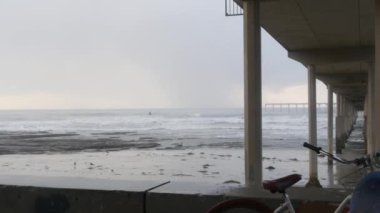 Yağmurlu havada Ocean Beach rıhtımı, sisli havada deniz dalgaları, Kaliforniya kıyıları, ABD. San Diego 'da, deniz kıyısındaki rıhtımda. Şiddetli sağanak altında puslu ve dramatik bir sahil. Demiryolu damlaları.