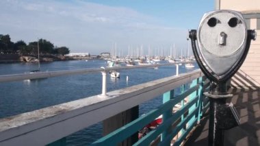 Limanda ya da körfezde yatlar, Monterey marinası, Old Fishermans Wharf, rıhtım ya da iskele, ABD. Sabit dürbünler, kule görüntüleyici ya da okyanus suyunun yanında teleskop. Sahilde sahil yürüyüşü