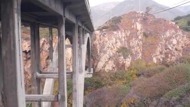キャニオン 太平洋岸高速道路の風光明媚な道路 カリフォルニア州の道路旅行 ビッグサー自然 米国の川のクリーク上のアーチ橋 Cabrillo高速道路1 海沿いの観光ルート 海溝の下の急な崖や岩 — ストック動画