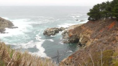Kayalık okyanus kıyısı, sisli sisli hava. Deniz dalgaları sahile çarpıyor. Kaliforniya manzarası, Big Sur doğa, ABD. Pasifik kıyısı karayolu uçurumdan ya da sarp kayalıklardan manzaralı.
