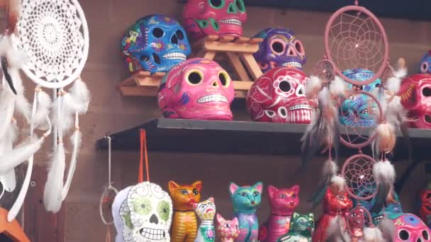 市場の屋台でメキシコのお土産 カラフルな塗装頭蓋骨や夢のキャッチャー 多色鮮やかな民族の装飾品 バザーや市場 カウンターで販売するためのセラミック細工の死のシンボル 死者の日 — ストック動画