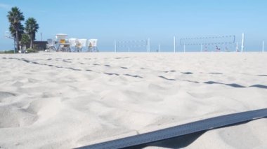 Plaj kortunda voleybol oynayan oyuncular, top ve ağla voleybol oyunu, Kaliforniya sahili, ABD. Spor sahasında odakları kesilmiş insanlar, kumlu okyanus kıyısında. Kusursuz döngüsüz sinemagraf arkaplanı.