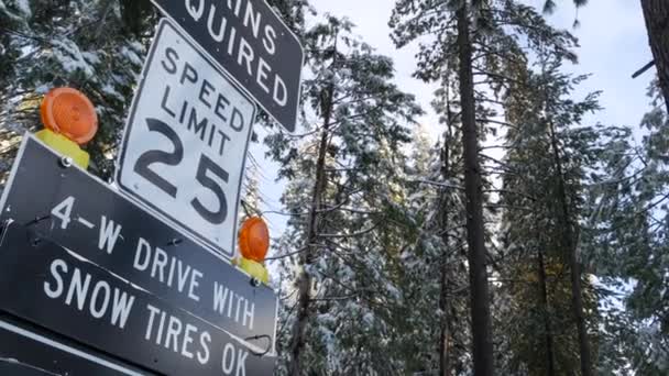 チェーンまたはスノータイヤは 交通標識 山岳冬の高速道路 ヨセミテ雪の森 カリフォルニア州アメリカを必要とした 氷の道路の注意や警告 輸送のための降雪中の安全性 森の中の制限速度 — ストック動画