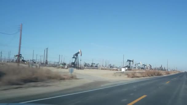 在美国加州油田有抽油泵孔的油井 在油田工作的原油矿物开采钻机 工业景观 沙漠峡谷中的井架 油井抽油机上的许多排气口平台 — 图库视频影像