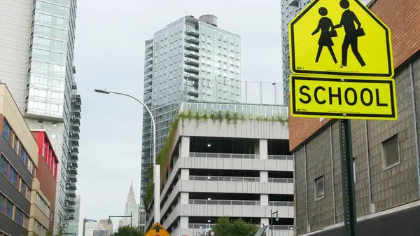 stock image School zone yellow road sign, pedestrian crossing. Children safety, New York City street. Transport and education symbol, USA. Traffic roadsign, Queens, Long Island. Manhattan view, Chrysler Building.