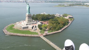 New York City 'nin kapıları helikopter uçuşuna kapalı, helikopter Amerika Birleşik Devletleri' nde Özgürlük Anıtı üzerinde uçuyor. - Evet. Spor ayakkabılı ayaklar, turist macerası, ayakkabılı bacaklar, selfie pov. Amerika 'ya git. Kamera sallanıyor..