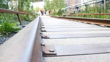 New York City High Line Greenway 'i yükseltti, Manhattan Midtown, ABD. Şehir parkındaki insanlar. Bahçedeki yeşillikte gezinti. Amerikan sokak hayatı, Hudson Yards yakınlarında Chelsea Highline. Demiryolu rayları.
