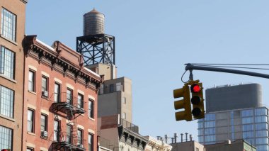 New York caddesi kavşağı, sarı trafik ışığı, ulaşım yolu kavşağı, Birleşik Devletler. Mimarlık. Çatı su kulesi, tank. Yangın merdivenli kırmızı kahverengi tuğlalı ev. Manhattan.