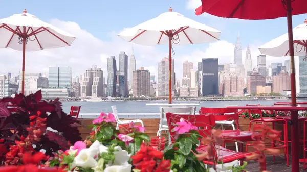 New York şehri kıyısı silueti, Manhattan şehir merkezi binaları, nehir kıyısındaki gökdelenler, doğu nehri kıyısındaki kafe şemsiyeleri. Hunters Point, Long Island, Queens, ABD 'den liman kenti manzarası.