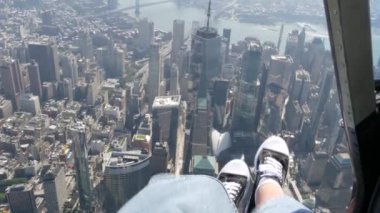 New York City 'nin kapıları helikopter uçuşuna kapalı. Helikopter Manhattan' ın üzerinde uçuyor. Dünya Ticaret Merkezi. Ayaklar spor ayakkabılarda, turist bacakları, ayakkabılar selfie pov. Amerika 'ya uçuk seyahat. Kamera sallanıyor..