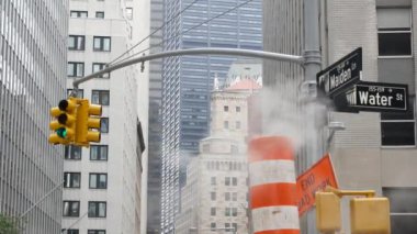 New York Su Sokağı 'nda buhar sızıntısı, turuncu buhar borusu yığını. Pipo dumanı. Con Edisons Buhar Operasyonları Sistemi, Manhattan şehir merkezi finans bölgesi mimarisi. Trafik ışığı