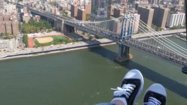 New York Şehri 'nin kapıları kapalı, helikopter Manhattan Brooklyn Köprüsü üzerinde uçuyor, Birleşik Devletler. Ayaklar ayakkabıda, bacaklar ayakkabıda, selfie pov. Ekstrem turist macerası, Amerika seyahati. Kamera sallanıyor..