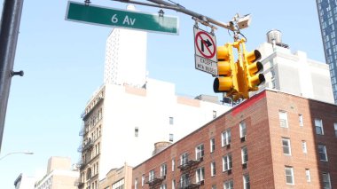 New York City kavşağı, sokak kavşağı tabelası. 6. Cadde, Americas Bulvarı köşe işareti, Midtown bölgesi, New York. Sarı trafik ışığı. Ev, kırmızı tuğla bina.