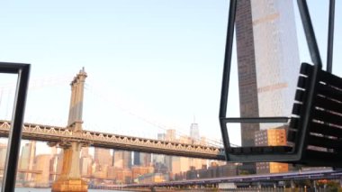 New York, Birleşik Devletler - 7 Eylül 2023: Manhattan Köprüsü 'nden Brooklyn' e. Rıhtım 35 salıncak bankı, şehir merkezinde deniz kenarı manzarası. Dünya Ticaret Merkezi gökdeleni, finans bölgesi sabah gün batımı.