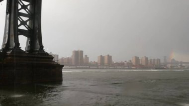 Brooklyn 'deki Manhattan Köprüsü' nün altında yağmurlu bir New York şehri. Doğu Nehri, Dumbo rıhtımından gökkuşağı. Nehir kıyısında sisli bir gün. Williamsburg Köprüsü John Caddesi Parkı 'ndan nehir suyu üzerinde