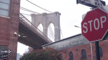 Dumbo 'dan New York City Brooklyn Köprüsü' ne. Kırmızı tuğla duvar, eski tarihi tütün deposu, Market ve Tiyatro. Düşük açı. Amerika Birleşik Devletleri 'ni gezmek, mimarlık. Tek yön ok, dur işareti..