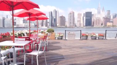 New York şehri kıyısı silueti, Manhattan şehir merkezi binaları, nehir kıyısındaki gökdelenler, doğu nehri kıyısındaki kafe şemsiyeleri. Hunters Point, Long Island, Queens, ABD 'den liman kenti manzarası.
