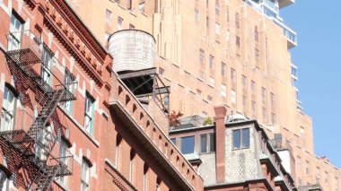New York City Manhattan mimarisi. Şehir dışındaki konutlar. ABD 'de gayrimenkul. Kırmızı tuğla cephe. Yangın çıkışı, acil merdiven çıkışı. Çatıdaki su kulesi, çatıdaki tank..