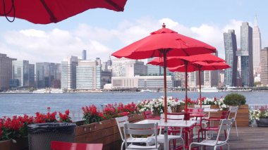 New York şehri kıyısı silueti, Manhattan şehir merkezi binaları, nehir kıyısındaki gökdelenler, doğu nehri kıyısındaki kafe şemsiyeleri. Hunters Point, Long Island, Queens, ABD 'den liman kenti manzarası.