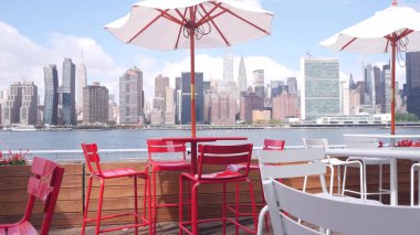 New York şehri kıyısı silueti, Manhattan şehir merkezi binaları, nehir kıyısındaki gökdelenler, doğu nehri kıyısındaki kafe şemsiyeleri. Hunters Point, Long Island, Queens, ABD 'den liman kenti manzarası.