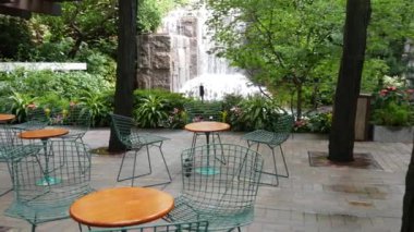 New York şehri hayatı, şehir parkı, Greenacre Park şelalesi. Amerikan Manhattan Midtown, ABD. Eğlence bölgesi yaz çiçekleri, ağaçlar yeşillik. Boş sandalyeler ve masalar. New York 'ta yeşil vaha.