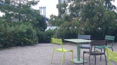 Manhattan Köprüsü 'nden Brooklyn Dumbo' ya. New York City sembolleri, ABD. Piknik alanı, masa ve boş sandalyeler, ağaçların arasında dinlenmek için bank, John Street Park. ABD Turizm Tarihi.