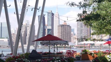 New York şehri kıyısı silueti, Manhattan şehir merkezi binaları, nehir kıyısındaki gökdelenler, doğu nehri suyu. Waterside şehir manzarası, Hunters Point rıhtım kolonları, Long Island, Queens. Birleşik Devletler.