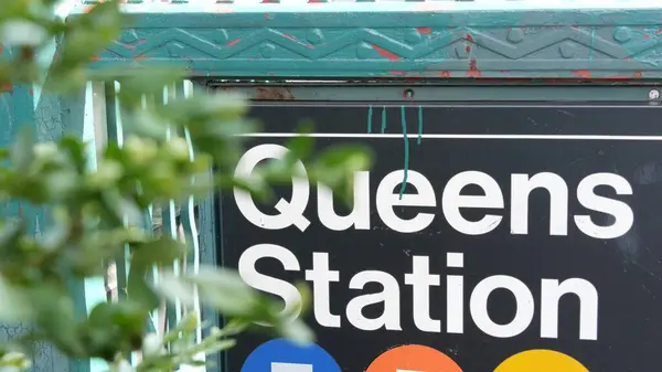 stock image New York subway sign, Queens underground metro station. Metropolitan entrance fence, public transport exit. Long Island city street, NYC United States. Navigation text on signboard. Passenger guidance