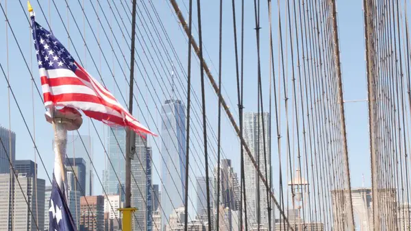 stock image Flag on Brooklyn Bridge, Manhattan downtown, New York City skyline, financial district cityscape. World Trade Center skyscraper. United States of America patriotic symbol of independence. Bridge cable