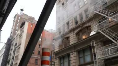 New York, Amerika Birleşik Devletleri, 8 Eylül 2023: Buhar borusu sokağa saçıldı, turuncu tüp yığını. Pipo dumanı. Con Edison Buhar Sistemi 5. Cadde, Manhattan. Yangın merdiveni, çatı kulesi tankı.