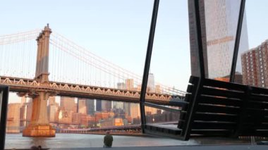 New York, Birleşik Devletler - 7 Eylül 2023: Manhattan Köprüsü 'nden Brooklyn' e. Rıhtım 35 salıncak bankı, şehir merkezinde deniz kenarı manzarası. Dünya Ticaret Merkezi gökdeleni, finans bölgesi sabah gün batımı.