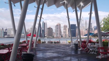 New York şehri kıyısı silueti, Manhattan şehir merkezi binaları, nehir kıyısındaki gökdelenler, doğu nehri suyu. Waterside şehir manzarası, Hunters Point rıhtım kolonları, Long Island, Queens. Birleşik Devletler.