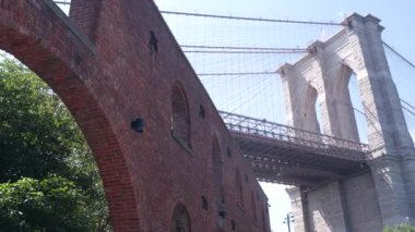 Dumbo 'dan New York City Brooklyn Köprüsü' ne. Kırmızı tuğla duvar, eski tarihi tütün deposu, Market ve Tiyatro. Düşük açı. Sembolik simge altında kemerli pencereler. Amerika Birleşik Devletleri, ABD mimarisi