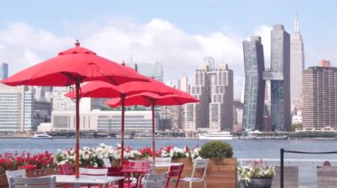New York şehri kıyısı silueti, Manhattan şehir merkezi binaları, nehir kıyısındaki gökdelenler, doğu nehri kıyısındaki kafe şemsiyeleri. Hunters Point, Long Island, Queens, ABD 'den liman kenti manzarası.