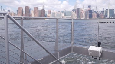 New York City skyline from ferry boat. Manhattan midtown highrise skyscrapers from ferryboat. East river waterfront panorama, riverfront architecture near water, USA. Empire State, Chrysler Building. clipart