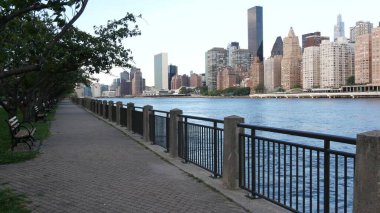 New York şehri kıyısı silueti, Manhattan şehir merkezi binaları, nehir kıyısındaki gökdelenler, doğu nehri suyu. Roosevelt Adası 'ndan deniz kenarı manzarası. Birleşik Devletler mimarisi ve gayrimenkul.