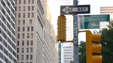 New York City kavşağı, sokak kavşağı tabelası. 6. Cadde, Americas Bulvarı köşe işareti, Midtown İş Bölgesi, New York taşımacılığı. Sarı trafik ışığı. Tek yönlü ok.