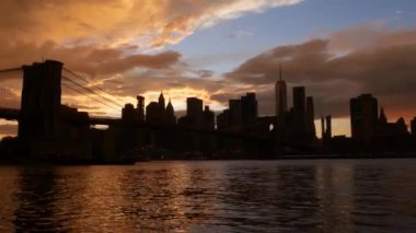 Brooklyn Köprüsü ve New York City Manhattan şehir merkezi silueti, finans bölgesi şehir manzarası. Birleşik Devletler Dünya Ticaret Merkezi gökdeleni. Waterfront Pebble Sahili, Dumbo, ABD. Dramatik gün batımı bulutlu gökyüzü