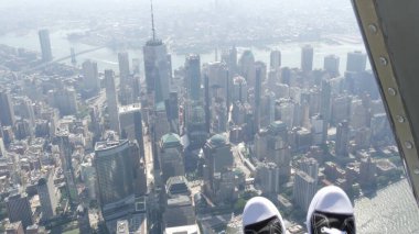 New York City 'nin kapıları helikopter uçuşuna kapalı. Helikopter Manhattan' ın üzerinde uçuyor. Dünya Ticaret Merkezi. Ayaklar spor ayakkabılarda, turist bacakları, ayakkabılar selfie pov. Amerika 'ya uçuk seyahat. Kamera sallanıyor..