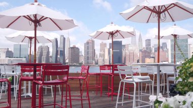 New York şehri kıyısı silueti, Manhattan şehir merkezi binaları, nehir kıyısındaki gökdelenler, doğu nehri kıyısındaki kafe şemsiyeleri. Hunters Point, Long Island, Queens, ABD 'den liman kenti manzarası.