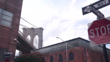 Dumbo 'dan New York City Brooklyn Köprüsü' ne. Kırmızı tuğla duvar, eski tarihi tütün deposu, Market ve Tiyatro. Düşük açı. Amerika Birleşik Devletleri 'ni gezmek, mimarlık. Tek yön ok, dur işareti..