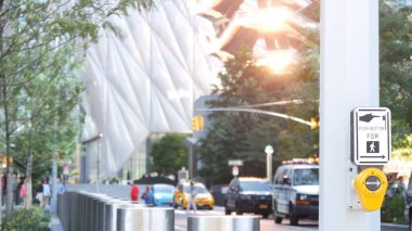 New York City Hudson Yards mimarisi Chelsea, Manhattan Midtown binası, NYC, ABD. Odaklanamayan insanlar, şehir trafiği, 34. Cadde. Gün batımı ışınları yansıması. Kesişen yol trafik ışığı düğmesi.